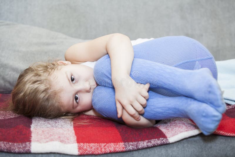 Little defenseless child huddled on the couch