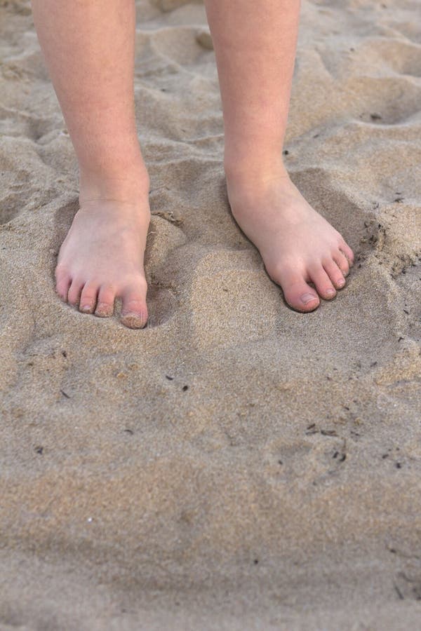 Little feet of boy or girl in beach sand