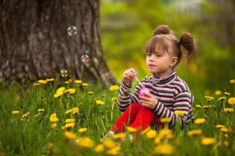 Little five-year girl blowing soap bubbles
