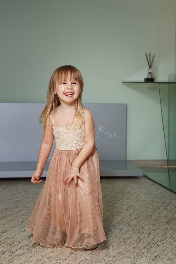 Little girl in a beautiful dress plays at home