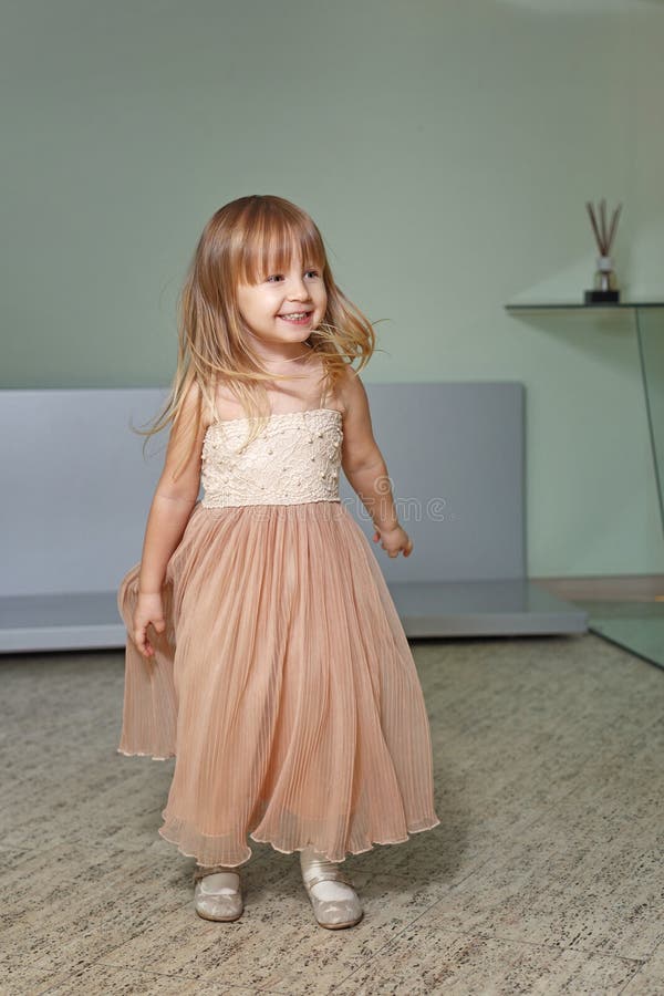 Little girl in a beautiful dress plays at home