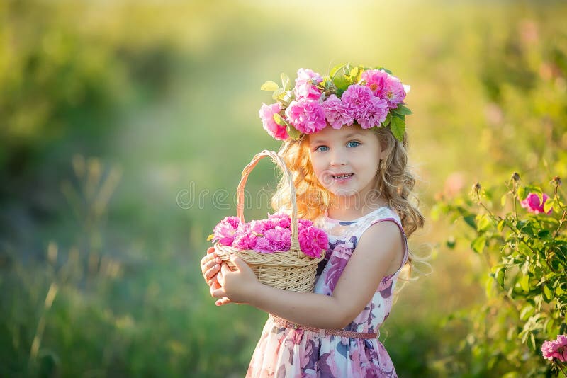 A little girl with beautiful long blond hair, dressed in a light dress and a wreath of real flowers on her head, in the
