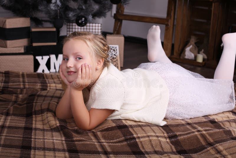 Little girl with blond hair wear elegant dress,posing beside Christmas tree