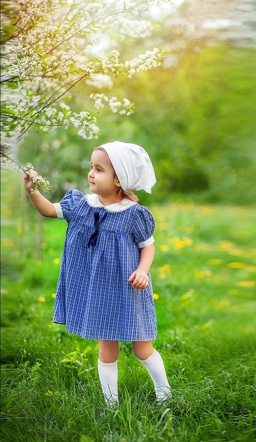 Little girl in a blooming garden. Retro vintage fashion