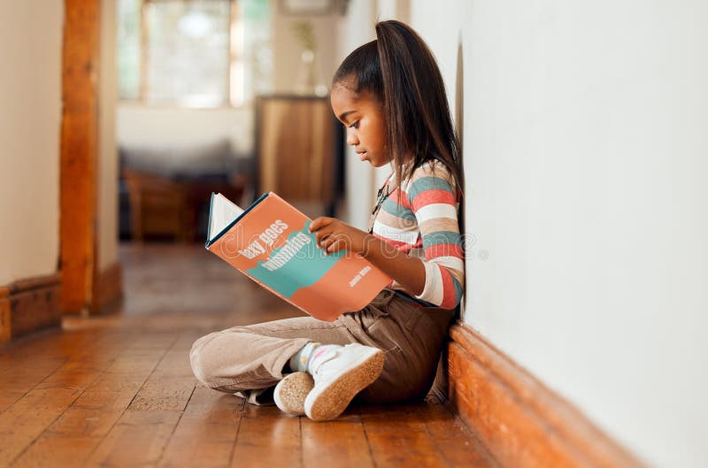 Little girl, book and reading on wooden floor for story time, learning or education relaxing at home with smile. Happy stock photo