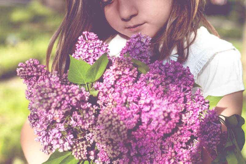 Little girl with bouquet of lilac in her hands