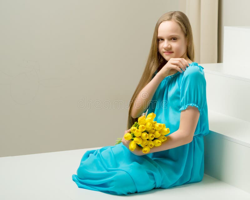 A little girl with a bouquet of tulips is sitting on the stairs. stock photography