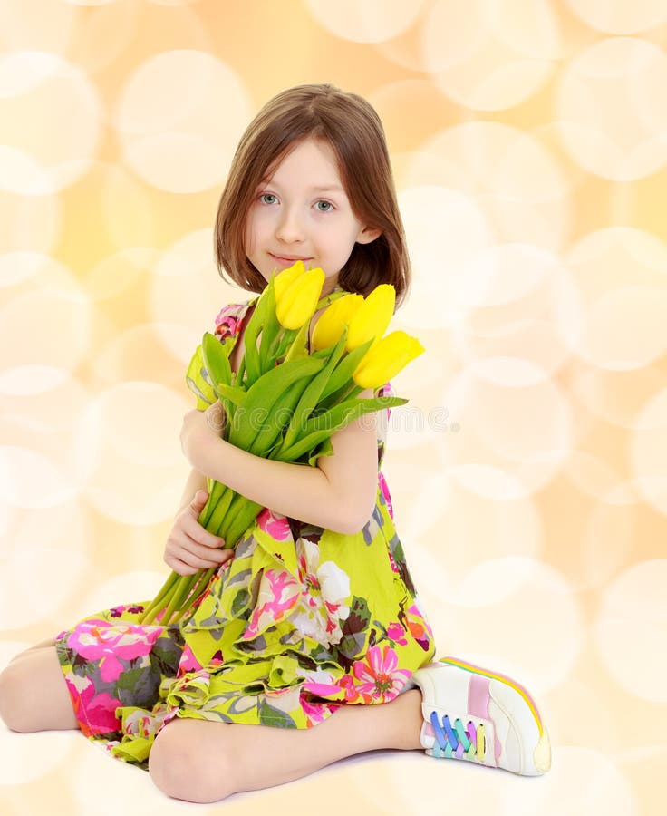 Little girl with a bouquet of yellow tulips.