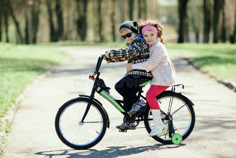 Little girl and boy riding on bicycle together