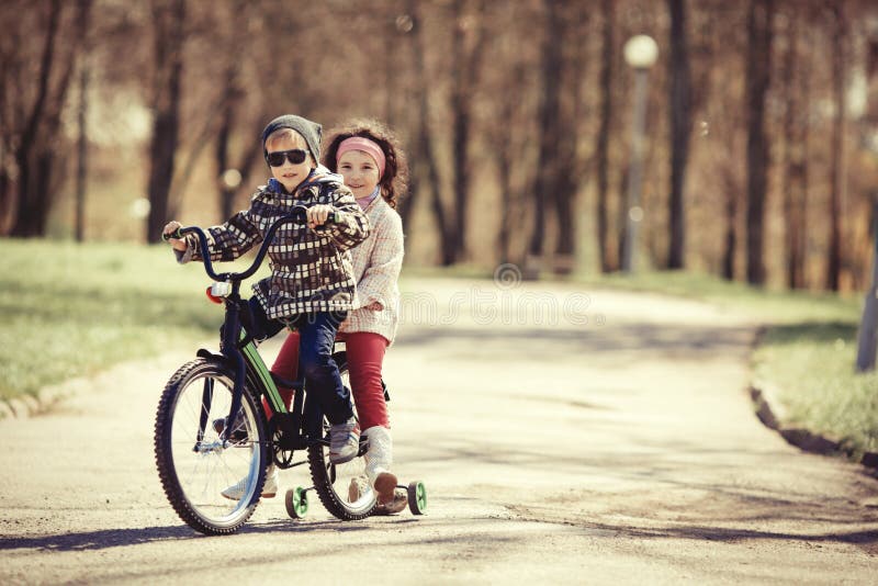 Little girl and boy riding on bicycle together