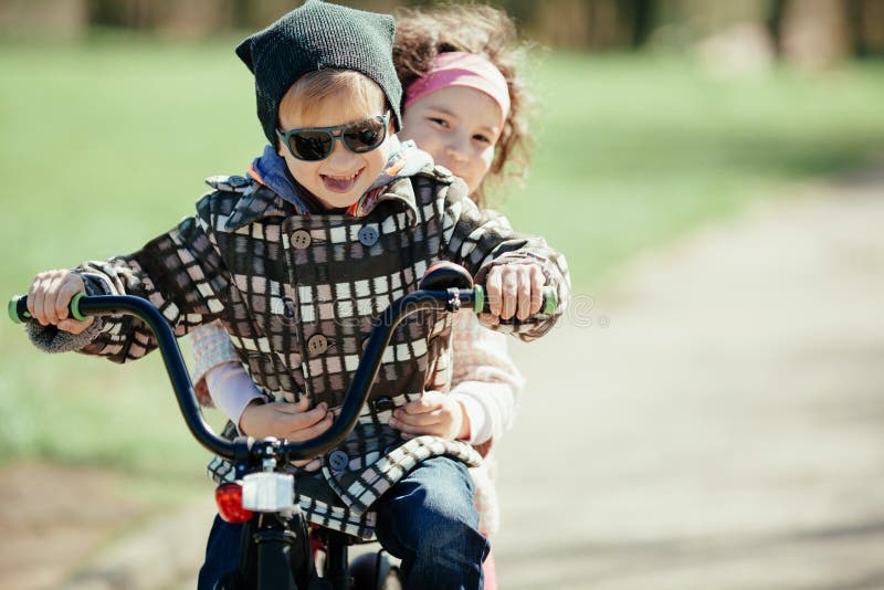 Little girl and boy riding on bicycle together