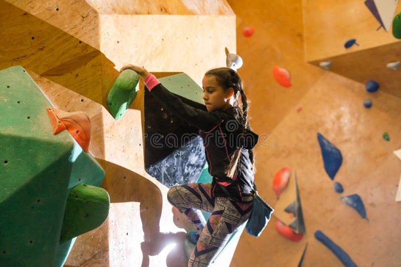 Little girl climbing a rock wall indoor royalty free stock image