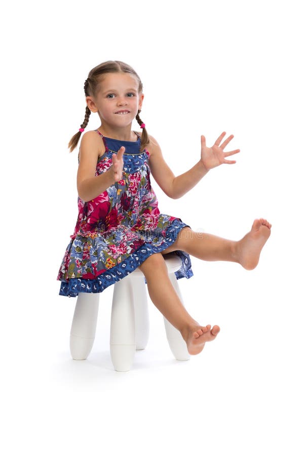 Little girl in a colored dress on a chair