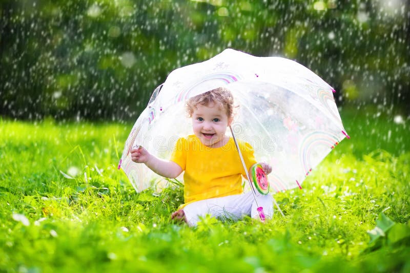 Little girl with colorful umbrella playing in the rain