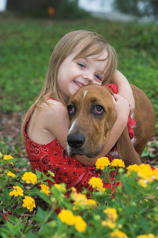Portrait of little girl with pet basset hound in flower bed, shallow focus. Portrait of little girl with pet basset hound in flower bed, shallow focus