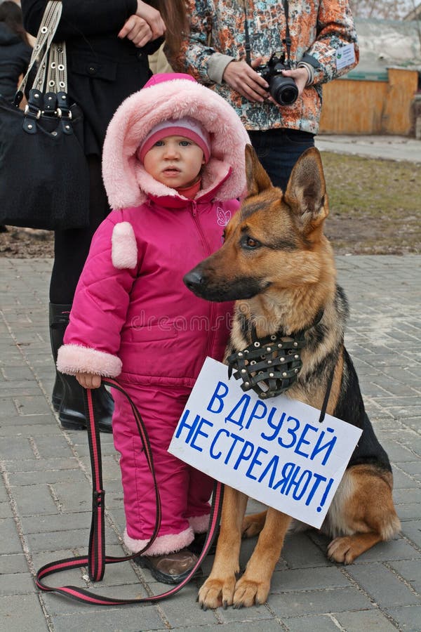 Little girl with dog with table translated from the Russian `Friends do not shoot!` in international action for the protection o stock photo Little girl with dog with table translated from the Russian `Friends do not shoot!` in international action for the protection o stock photo