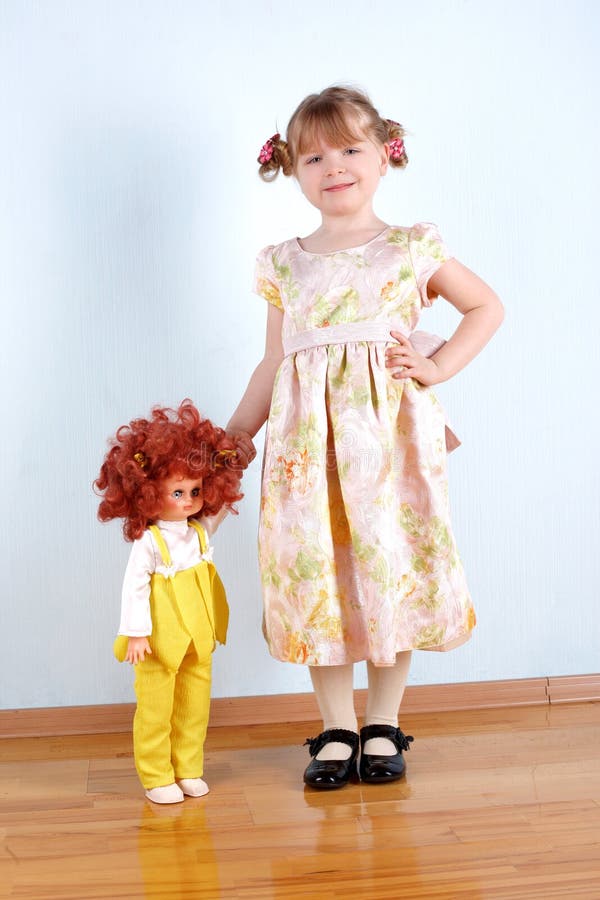 Little girl with doll at wall