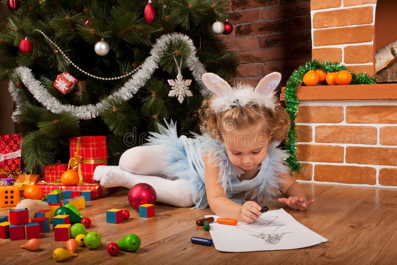 Little girl drawing near Christmas tree