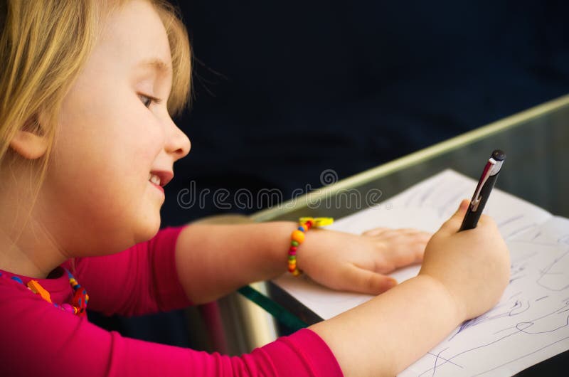 Little girl drawing with pen