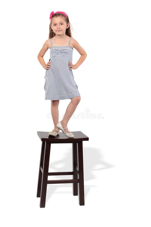 Little girl in dress stands on stool
