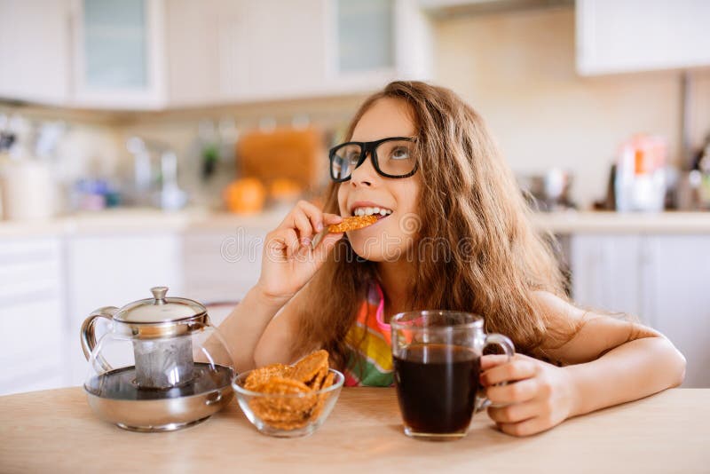 Little girl drink tea and eat cookies