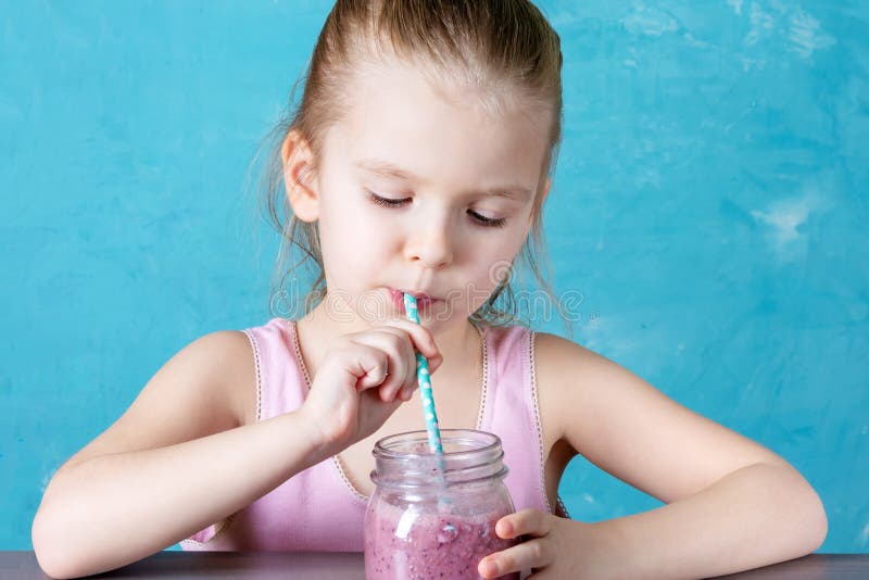 A little girl drinks smoothies through a straw. Healthy drink.