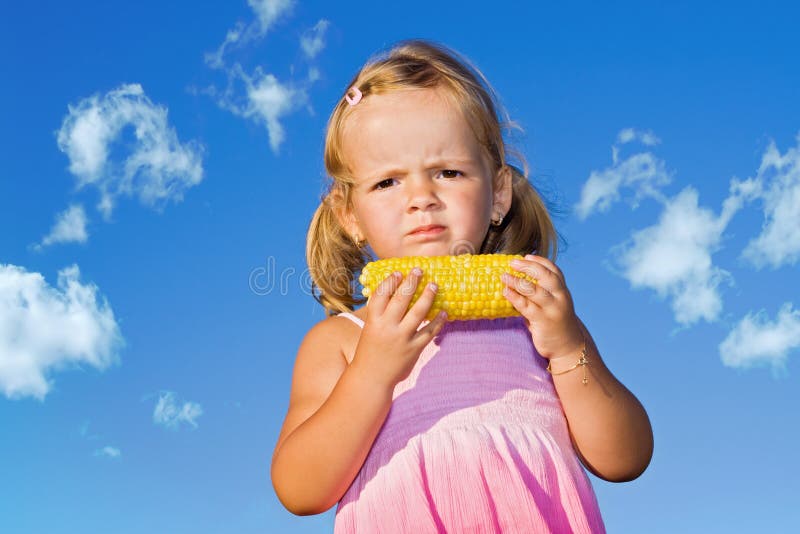 Little girl eating cooked sweet corn