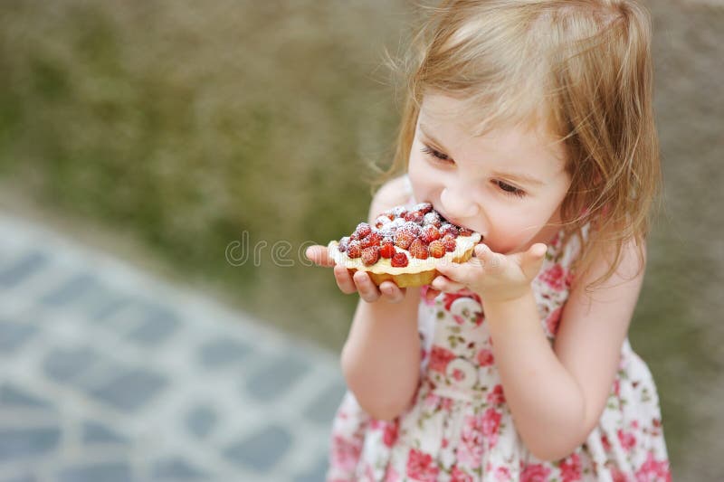 Little girl eating a strawberry tart
