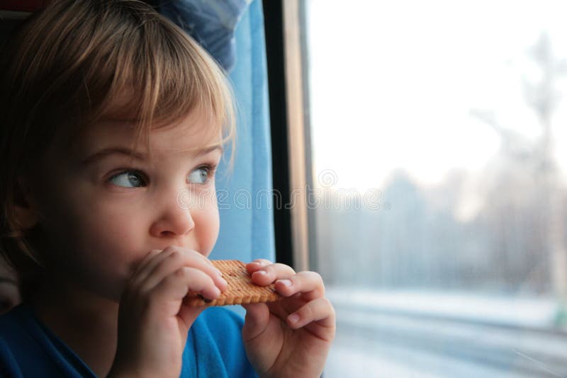 Little girl eats cookies and looks in window