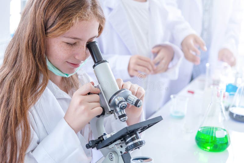 Little girl at an elementary school, using microscope research, testing in science class. Toddler girl doing biochemistry research royalty free stock image