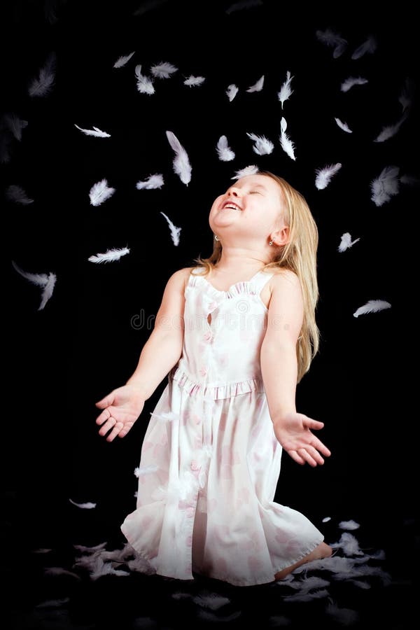 Little girl with falling white feathers royalty free stock photos