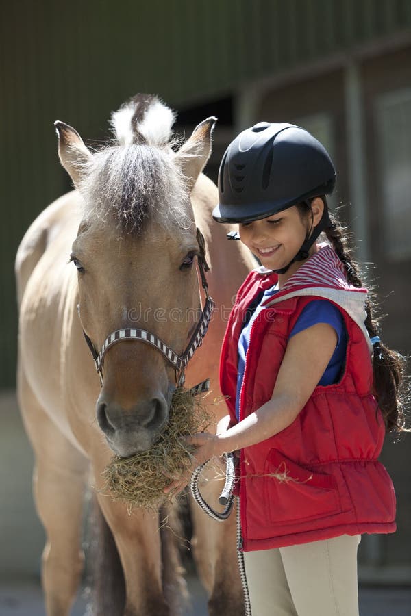 Little girl feeding her favorite horse some hay