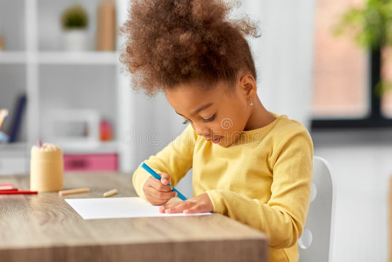 little girl with felt pen drawing picture at home