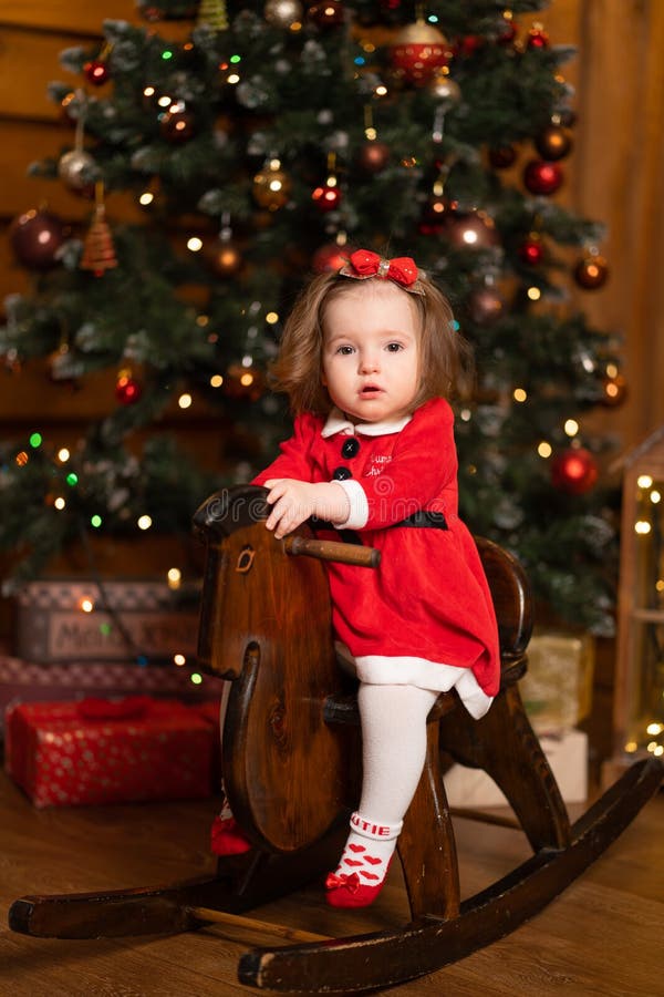 Little Girl in a Festive Red Dress on a Wooden Swing Rocking Horse ...