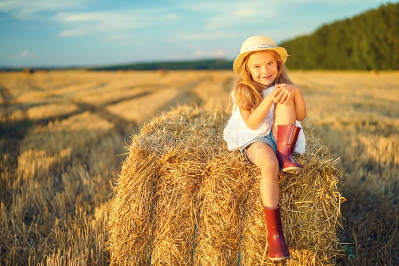 Little girl in a field with hay rolls