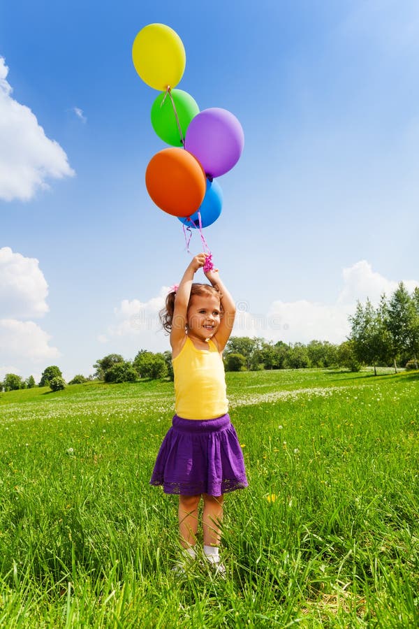 Little girl with flying balloons in the air