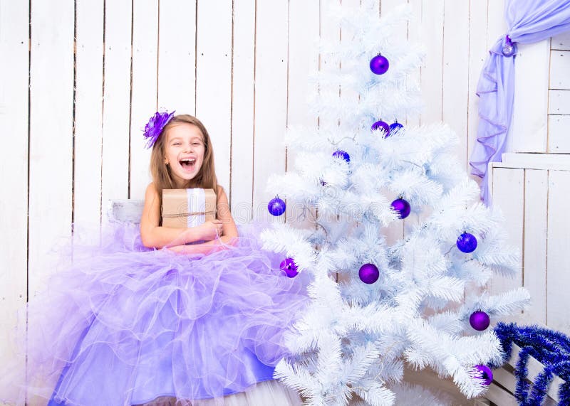 Little girl with a gift near Christmas tree