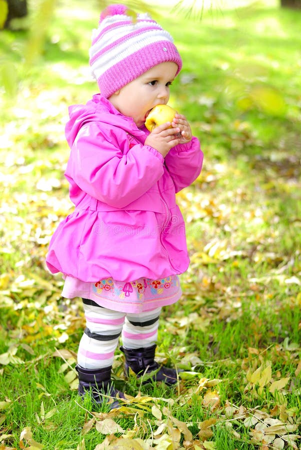 The little girl on a glade with an apple