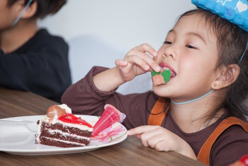 Little girl with hat eating birthday cake stock image Little girl with hat eating birthday cake stock image