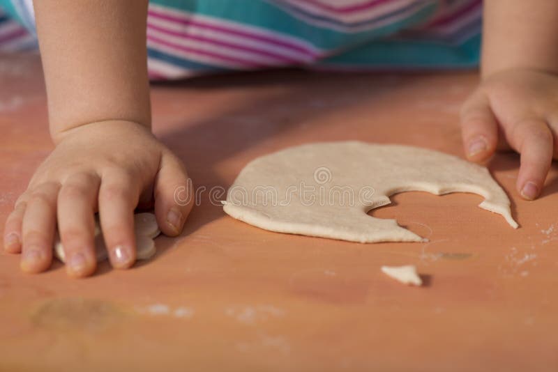 Little chef hands smeary with flour cutting the dough in flower shaped. Little chef hands smeary with flour cutting the dough in flower shaped