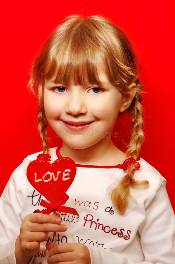 Little girl with heart shape lolly. 