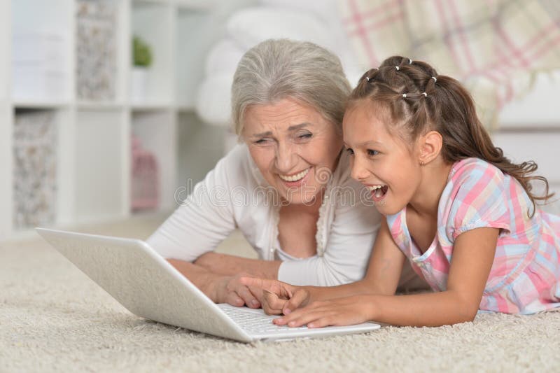 Little girl with her grandmother using laptop