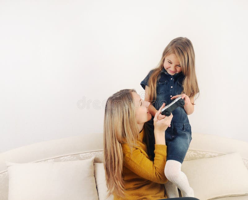 Little girl with her mother playing TV video game device on the