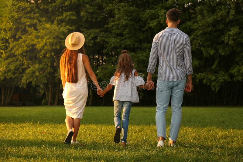 Little girl and her parents holding hands in park royalty free stock photo Little girl and her parents holding hands in park royalty free stock photo