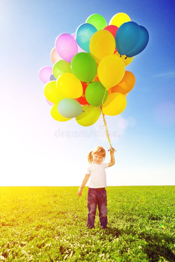Little girl holding colorful balloons. Child playing on a green stock photos Little girl holding colorful balloons. Child playing on a green stock photos