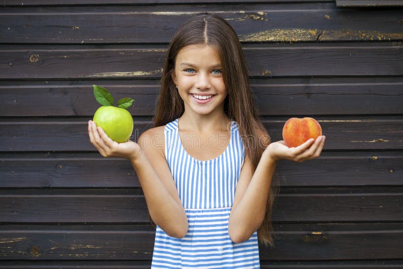 Little girl holding a green apple and a peach