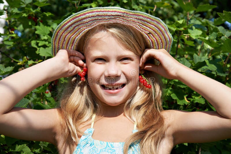 Little girl holding red currants near her ears