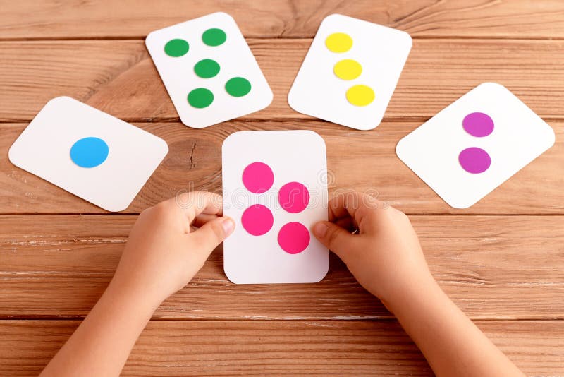 Little girl holds a flash card in his hands and learns the color, shape, quantity. Colorful flash cards for fun teaching children