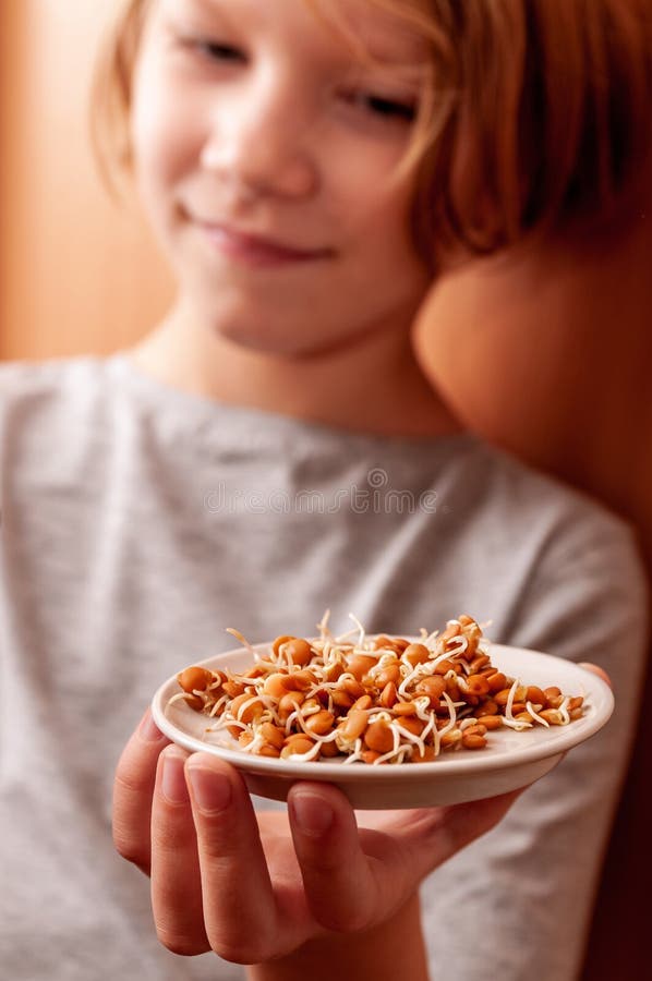 A little girl holds a plate of sprouted lentils royalty free stock image