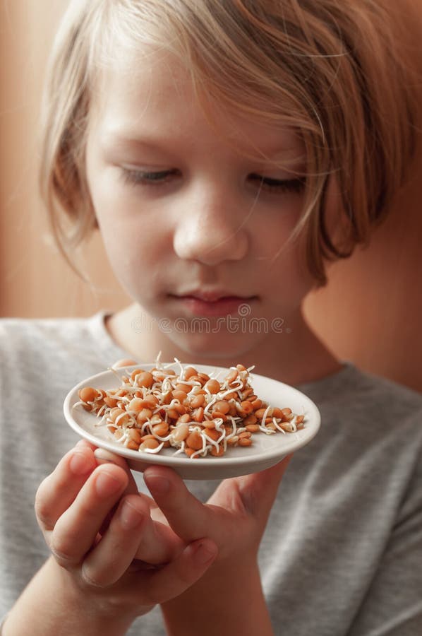 A little girl holds a plate of sprouted lentils royalty free stock photos